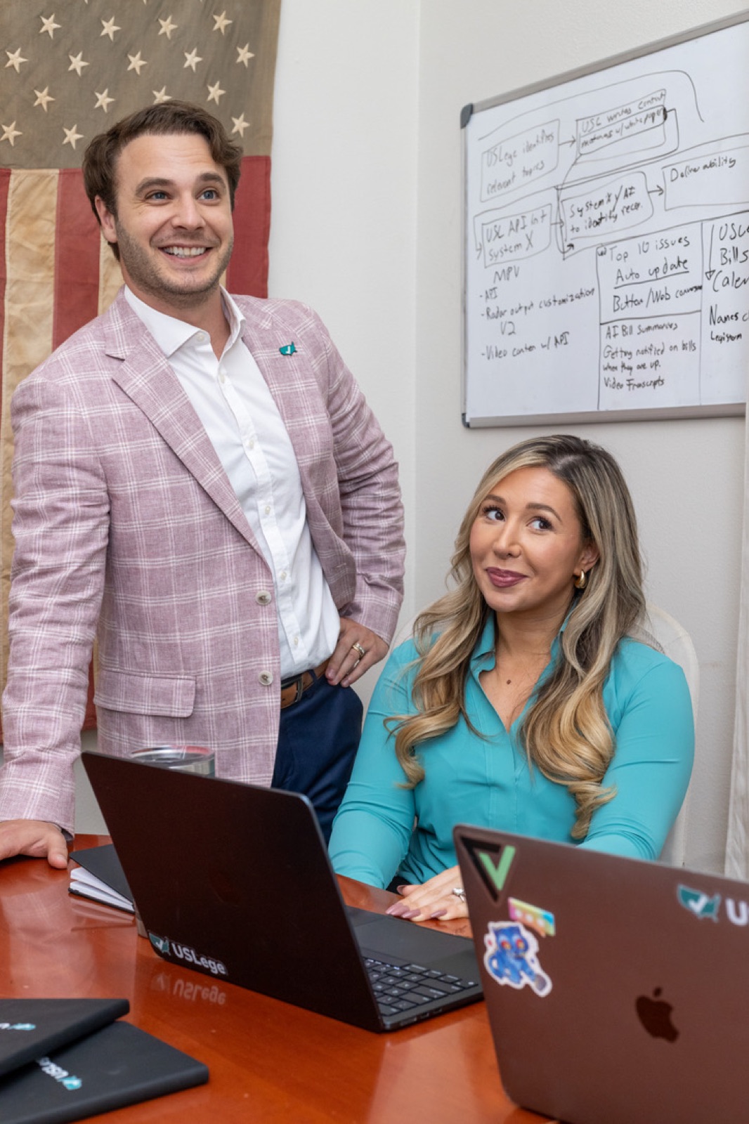 USLege co-founders Eric and Laura Davis working at a desk beneath an American flag